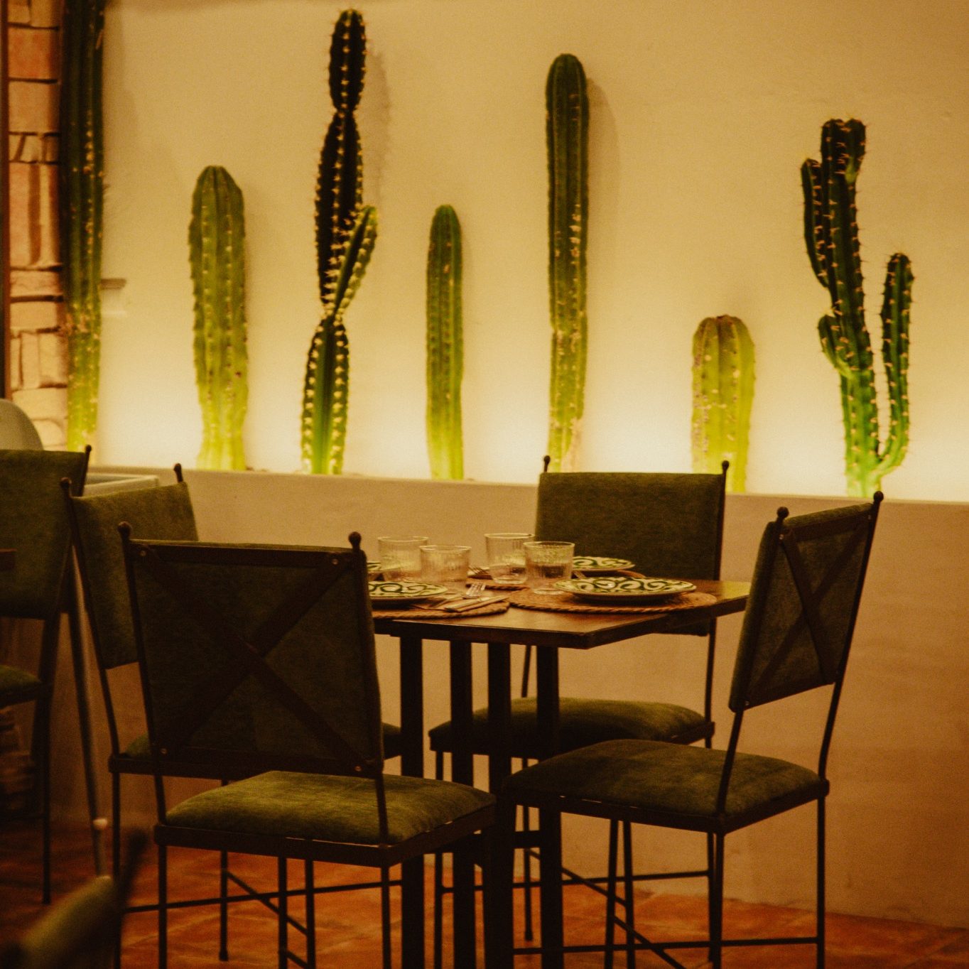 Detalle de una mesa de Casa Milpa rodeada de cactus y elementos decorativos mexicanos.